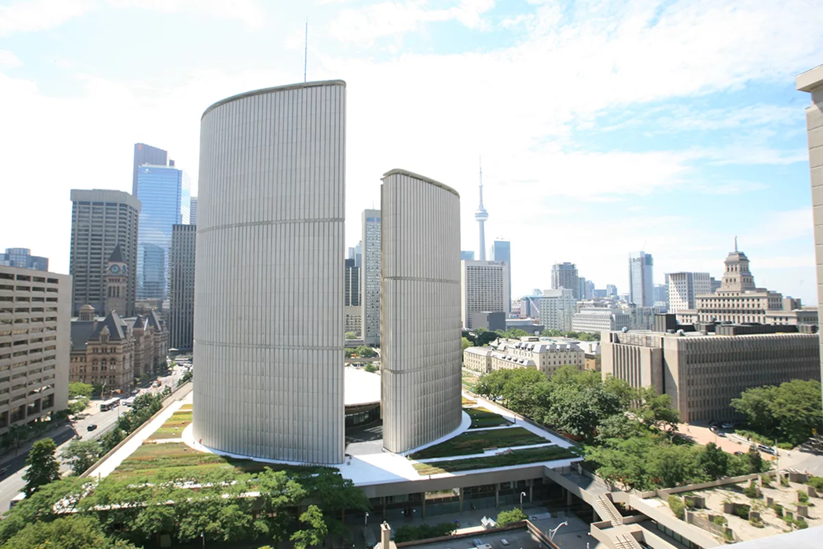 Toronto City Hall building surrounded by green roof modules, the city of Toronto in the background.